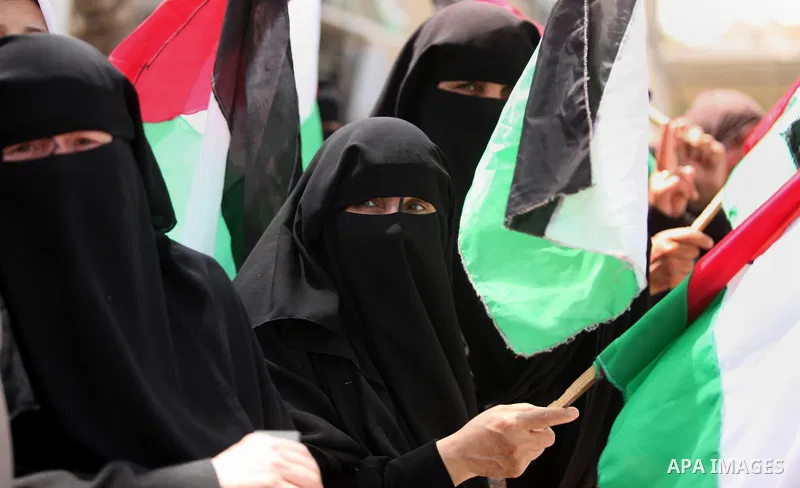 Palestinian women hold national flags during a demonstration to calling for an end in the political division and the national reconciliation in Gaza city, on April 26, 2016. Photo by Ashraf Amra