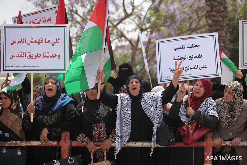 Palestinian women hold national flags during a demonstration to calling for an end in the political division and the national reconciliation in Gaza city, on April 26, 2016. Photo by Ashraf Amra