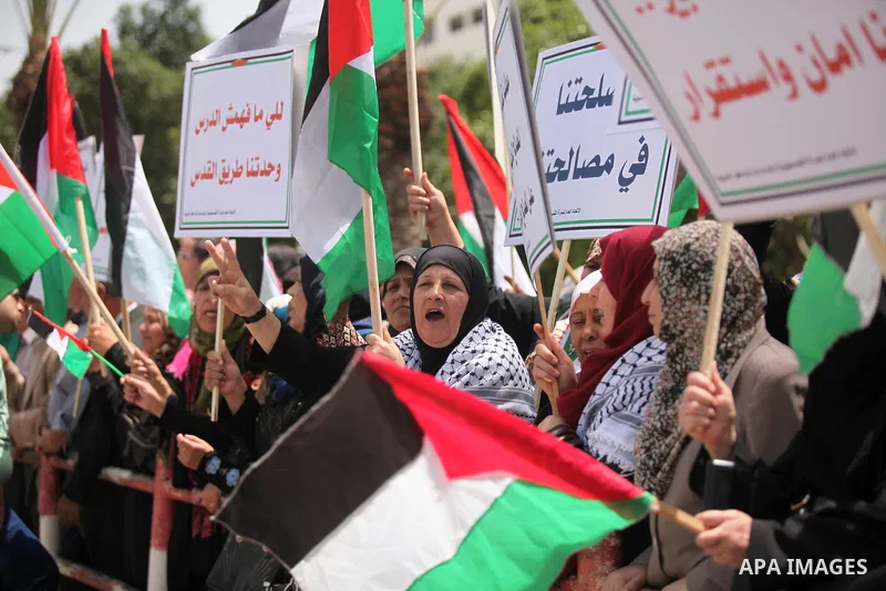 Palestinian women hold national flags during a demonstration to calling for an end in the political division and the national reconciliation in Gaza city, on April 26, 2016. Photo by Ashraf Amra