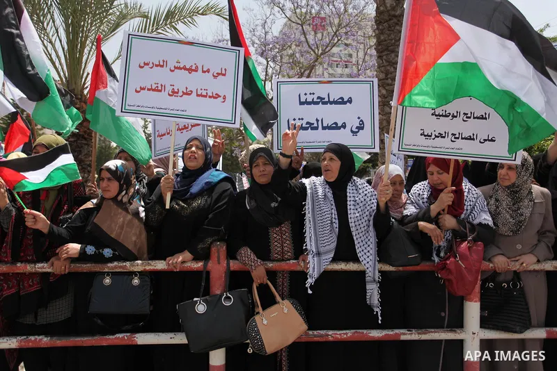 Palestinian women hold national flags during a demonstration to calling for an end in the political division and the national reconciliation in Gaza city, on April 26, 2016. Photo by Ashraf Amra