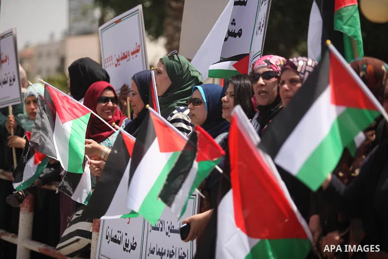 Palestinian women hold national flags during a demonstration to calling for an end in the political division and the national reconciliation in Gaza city, on April 26, 2016. Photo by Ashraf Amra
