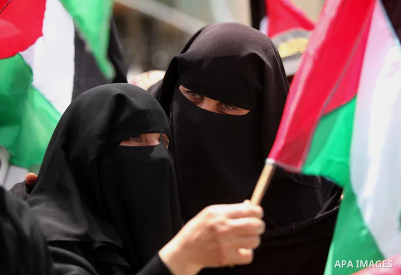 Palestinian women hold national flags during a demonstration to calling for an end in the political division and the national reconciliation in Gaza city, on April 26, 2016. Photo by Ashraf Amra