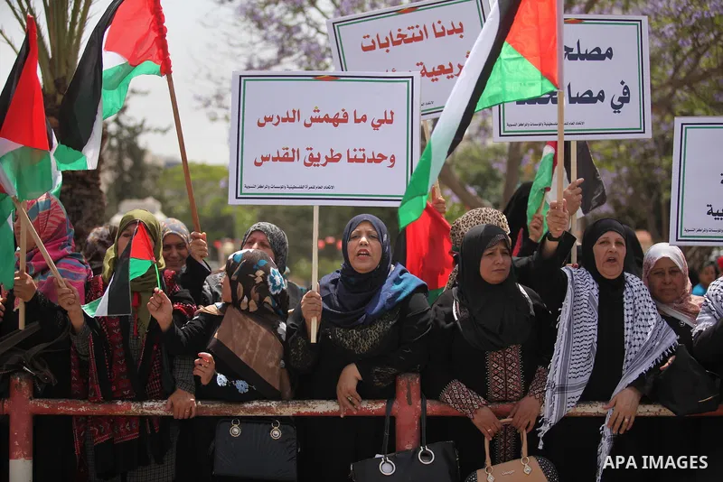 Palestinian women hold national flags during a demonstration to calling for an end in the political division and the national reconciliation in Gaza city, on April 26, 2016. Photo by Ashraf Amra