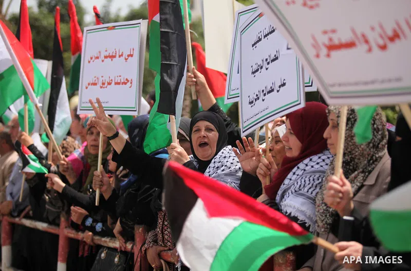 Palestinian women hold national flags during a demonstration to calling for an end in the political division and the national reconciliation in Gaza city, on April 26, 2016. Photo by Ashraf Amra