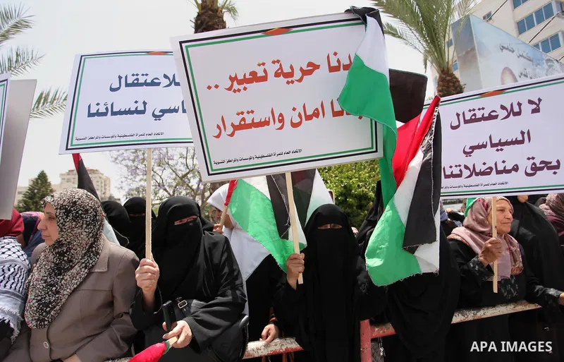 Palestinian women hold national flags during a demonstration to calling for an end in the political division and the national reconciliation in Gaza city, on April 26, 2016. Photo by Ashraf Amra
