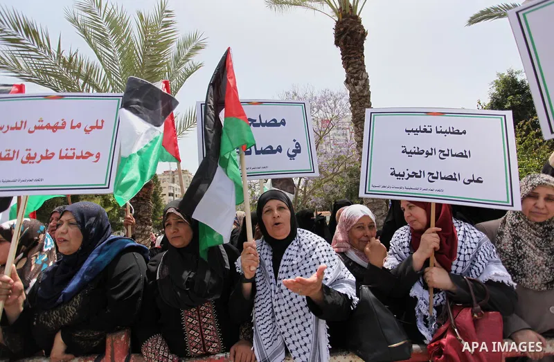 Palestinian women hold national flags during a demonstration to calling for an end in the political division and the national reconciliation in Gaza city, on April 26, 2016. Photo by Ashraf Amra