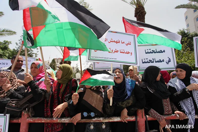 Palestinian women hold national flags during a demonstration to calling for an end in the political division and the national reconciliation in Gaza city, on April 26, 2016. Photo by Ashraf Amra