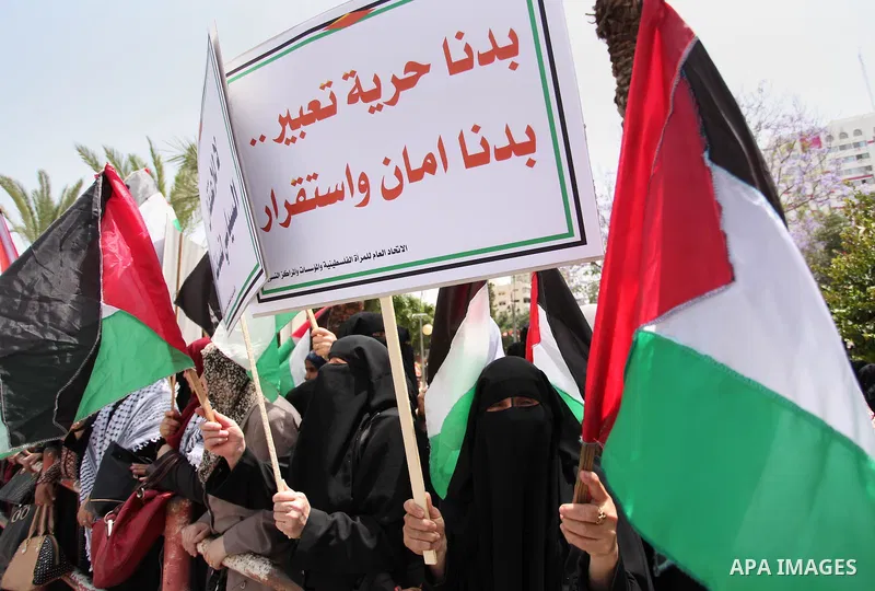 Palestinian women hold national flags during a demonstration to calling for an end in the political division and the national reconciliation in Gaza city, on April 26, 2016. Photo by Ashraf Amra