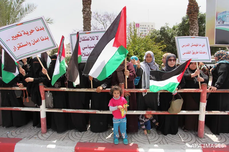 Palestinian women hold national flags during a demonstration to calling for an end in the political division and the national reconciliation in Gaza city, on April 26, 2016. Photo by Ashraf Amra
