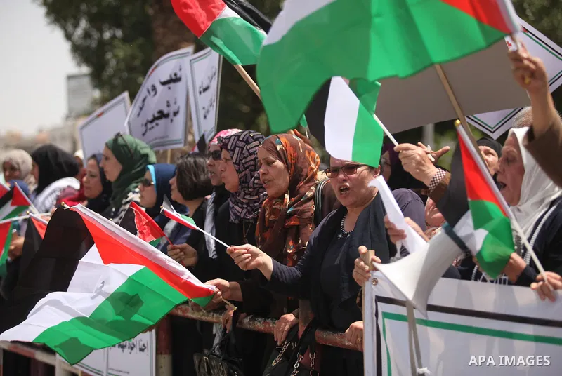 Palestinian women hold national flags during a demonstration to calling for an end in the political division and the national reconciliation in Gaza city, on April 26, 2016. Photo by Ashraf Amra