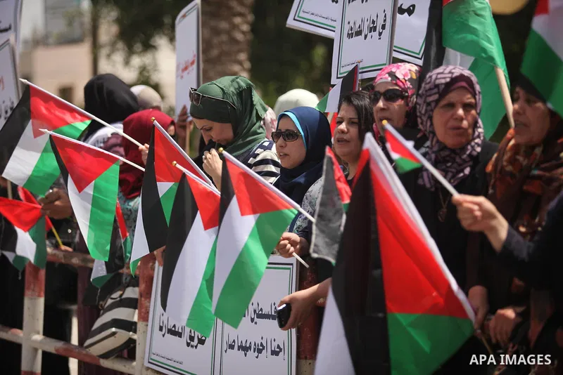 Palestinian women hold national flags during a demonstration to calling for an end in the political division and the national reconciliation in Gaza city, on April 26, 2016. Photo by Ashraf Amra