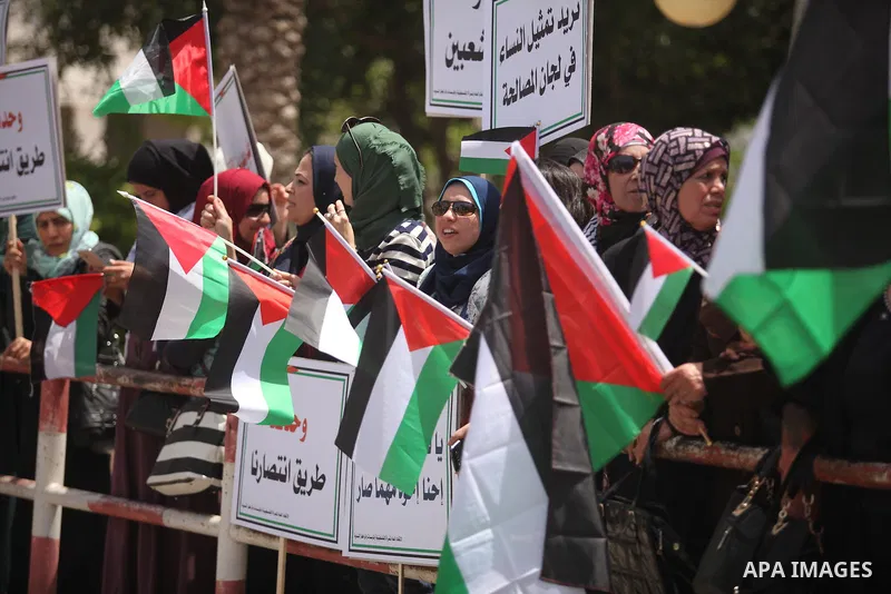 Palestinian women hold national flags during a demonstration to calling for an end in the political division and the national reconciliation in Gaza city, on April 26, 2016. Photo by Ashraf Amra