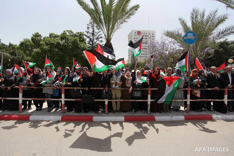 Palestinian women hold national flags during a demonstration to calling for an end in the political division and the national reconciliation in Gaza city, on April 26, 2016. Photo by Ashraf Amra