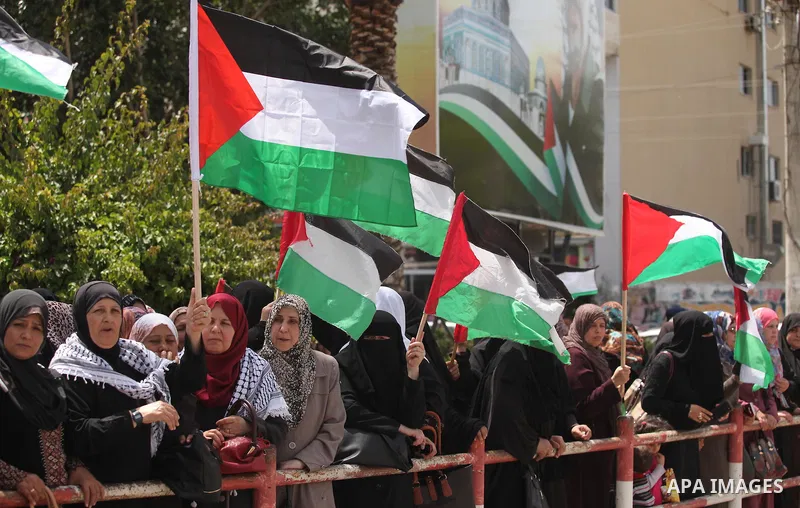 Palestinian women hold national flags during a demonstration to calling for an end in the political division and the national reconciliation in Gaza city, on April 26, 2016. Photo by Ashraf Amra
