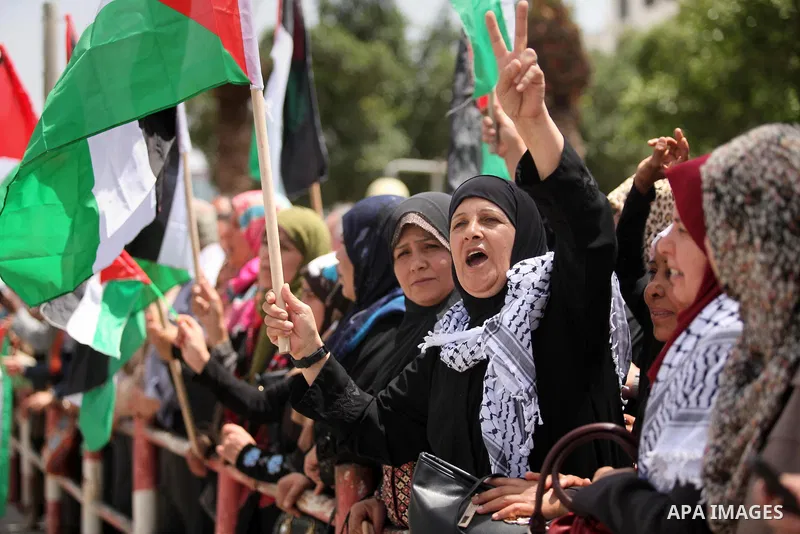 Palestinian women hold national flags during a demonstration to calling for an end in the political division and the national reconciliation in Gaza city, on April 26, 2016. Photo by Ashraf Amra
