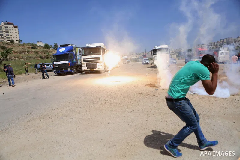 Palestinian journalists run for cover from a tear gas canister fired by Israeli troops during a protest calling for the release of Palestinian journalist Omar Nazal, who is held by Israel, near Israel's Ofer Prison near...
