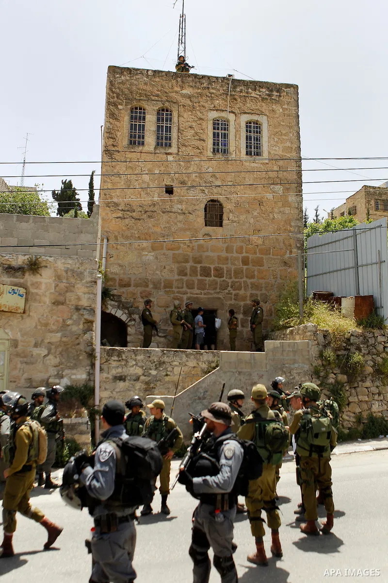 Israeli troops stand guard as Israeli settlers have a tour during the Jewish holiday of Passover in the West Bank city of Hebron, on April 26, 2016. Photo by Wisam Hashlamoun