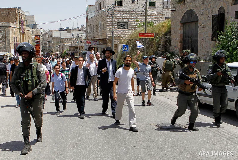 Israeli troops stand guard as Israeli settlers have a tour during the Jewish holiday of Passover in the West Bank city of Hebron, on April 26, 2016. Photo by Wisam Hashlamoun