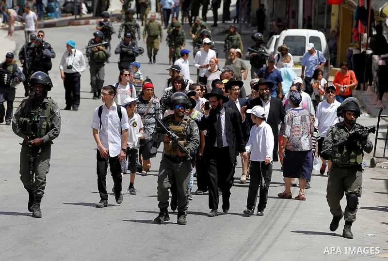 Israeli troops stand guard as Israeli settlers have a tour during the Jewish holiday of Passover in the West Bank city of Hebron, on April 26, 2016. Photo by Wisam Hashlamoun