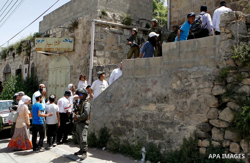 Israeli troops stand guard as Israeli settlers have a tour during the Jewish holiday of Passover in the West Bank city of Hebron, on April 26, 2016. Photo by Wisam Hashlamoun