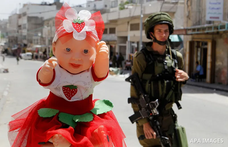 Israeli troops stand guard as Israeli settlers have a tour during the Jewish holiday of Passover in the West Bank city of Hebron, on April 26, 2016. Photo by Wisam Hashlamoun
