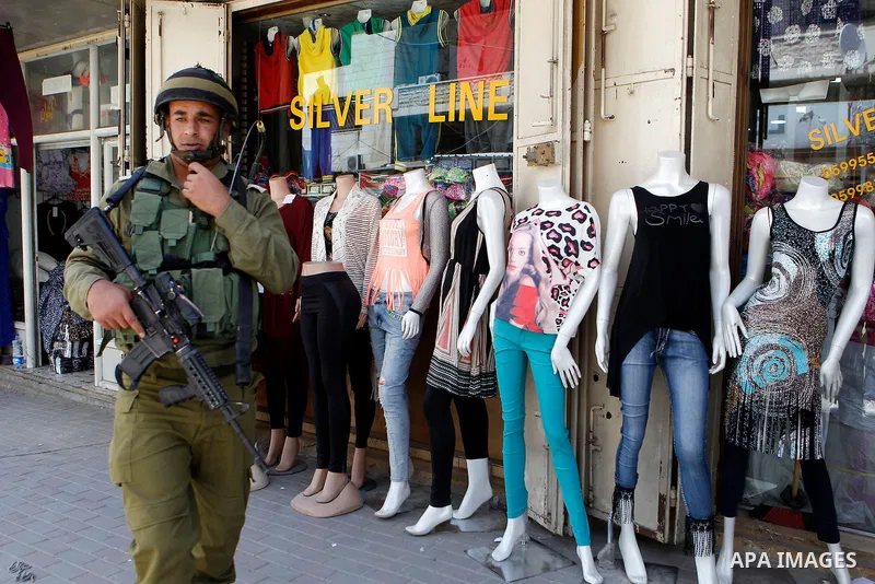 Israeli troops stand guard as Israeli settlers have a tour during the Jewish holiday of Passover in the West Bank city of Hebron, on April 26, 2016. Photo by Wisam Hashlamoun