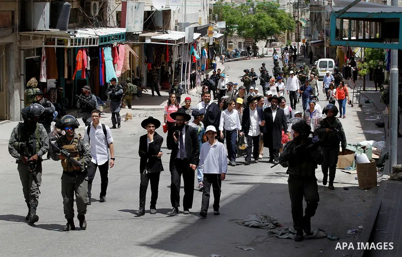 Israeli troops stand guard as Israeli settlers have a tour during the Jewish holiday of Passover in the West Bank city of Hebron, on April 26, 2016. Photo by Wisam Hashlamoun