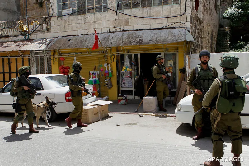 Israeli troops stand guard as Israeli settlers have a tour during the Jewish holiday of Passover in the West Bank city of Hebron, on April 26, 2016. Photo by Wisam Hashlamoun