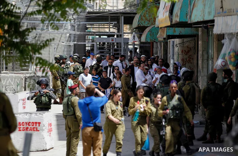 Israeli troops stand guard as Israeli settlers have a tour during the Jewish holiday of Passover in the West Bank city of Hebron, on April 26, 2016. Photo by Wisam Hashlamoun