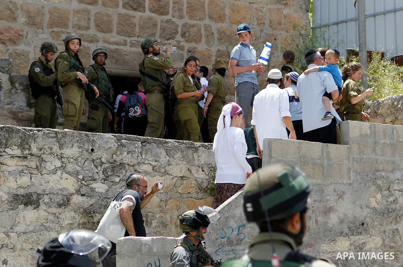 Israeli troops stand guard as Israeli settlers have a tour during the Jewish holiday of Passover in the West Bank city of Hebron, on April 26, 2016. Photo by Wisam Hashlamoun