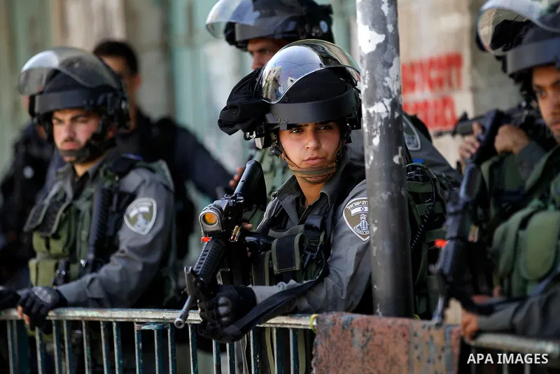 Israeli troops stand guard as Israeli settlers have a tour during the Jewish holiday of Passover in the West Bank city of Hebron, on April 26, 2016. Photo by Wisam Hashlamoun