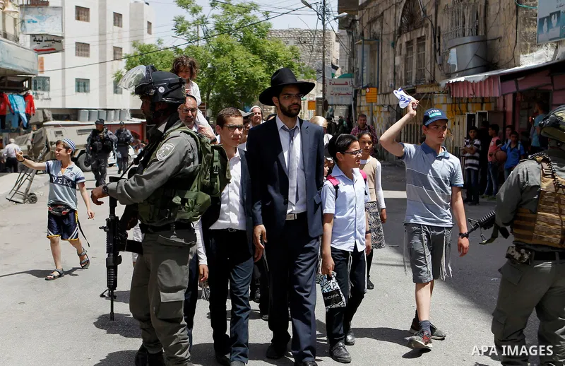 Israeli troops stand guard as Israeli settlers have a tour during the Jewish holiday of Passover in the West Bank city of Hebron, on April 26, 2016. Photo by Wisam Hashlamoun