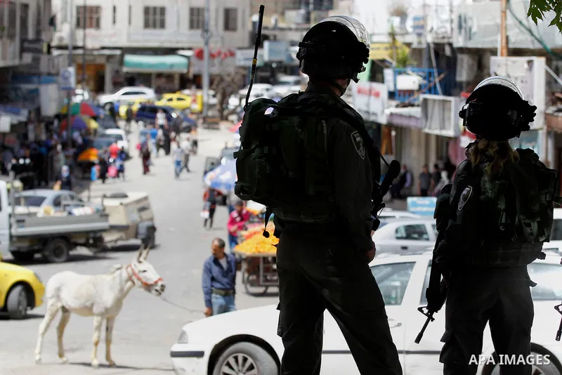 Israeli troops stand guard as Israeli settlers have a tour during the Jewish holiday of Passover in the West Bank city of Hebron, on April 26, 2016. Photo by Wisam Hashlamoun