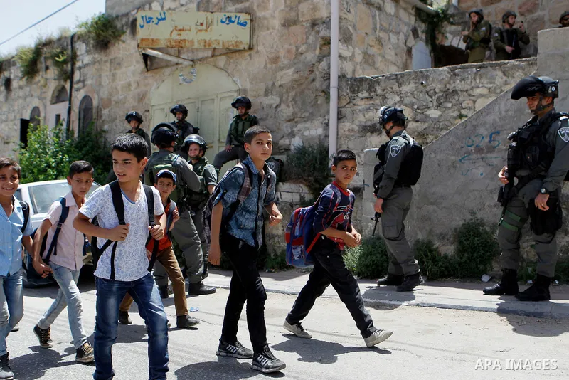 Israeli troops stand guard as Israeli settlers have a tour during the Jewish holiday of Passover in the West Bank city of Hebron, on April 26, 2016. Photo by Wisam Hashlamoun