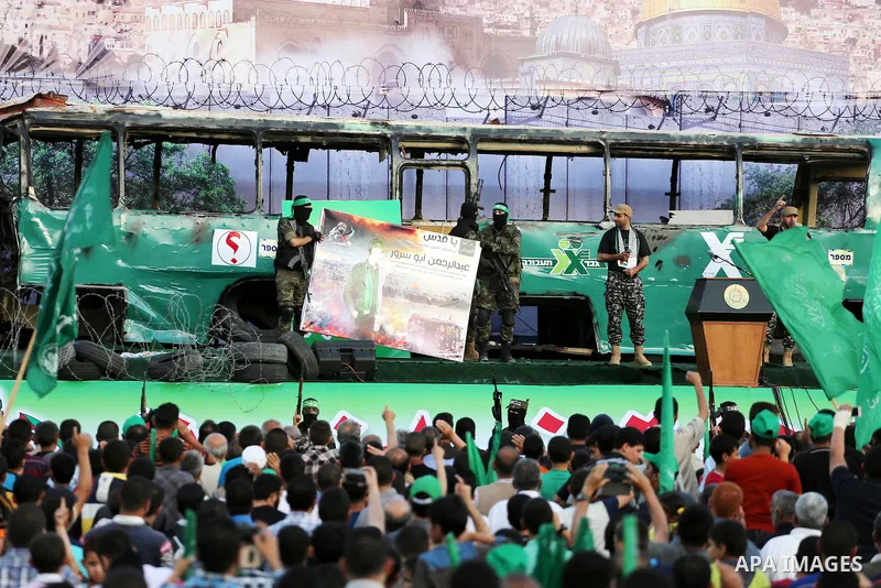 Palestinian Hamas militants march in front of a mock burnt Israeli bus during an anti-Israel rally in Gaza city April 28, 2016. Photo by Mohammed Asad