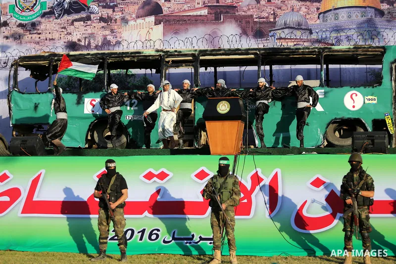 Palestinian Hamas militants march in front of a mock burnt Israeli bus during an anti-Israel rally in Gaza city April 28, 2016. Photo by Mohammed Asad