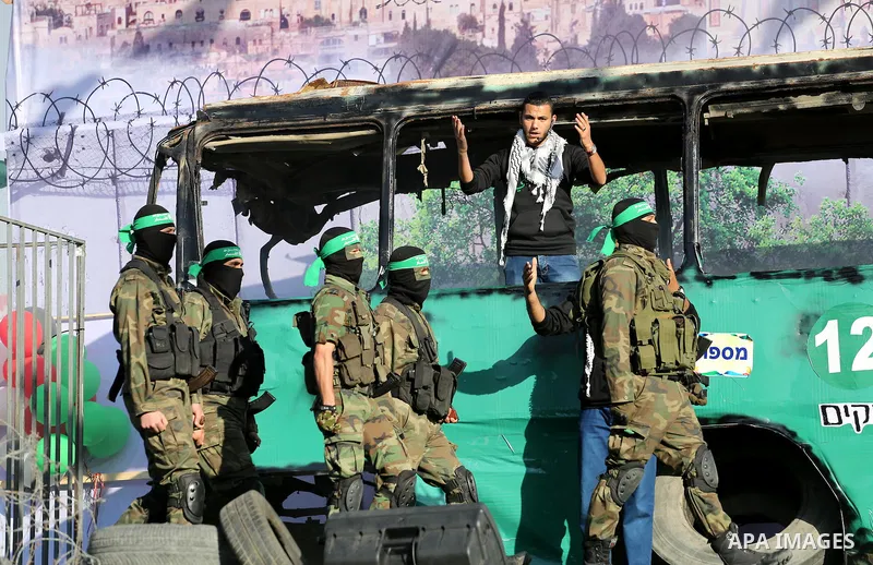 Palestinian Hamas militants march in front of a mock burnt Israeli bus during an anti-Israel rally in Gaza city April 28, 2016. Photo by Mohammed Asad