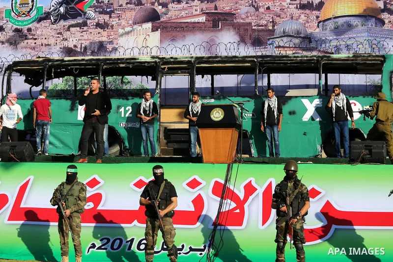Palestinian Hamas militants march in front of a mock burnt Israeli bus during an anti-Israel rally in Gaza city April 28, 2016. Photo by Mohammed Asad