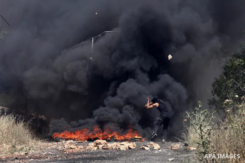 A Palestinian protester hurls stones towards a digger operated by Israeli security forces during clashes following a demonstration against the expropriation of Palestinian land by Israel on April 29, 2016 in the village...