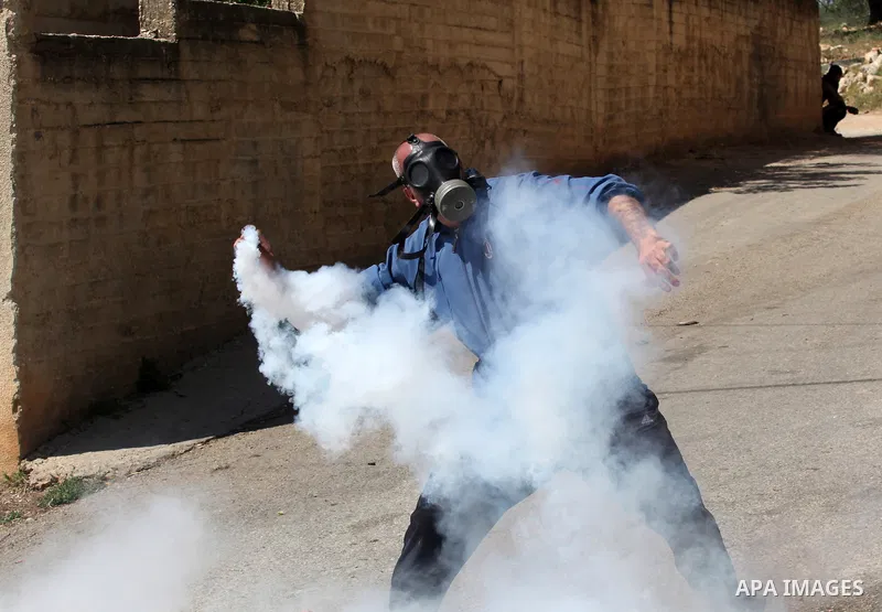 A Palestinian protester throws back a tear gas canister fired by Israeli security forces during clashes following a demonstration against the expropriation of Palestinian land by Israel on April 29, 2016 in the village o...