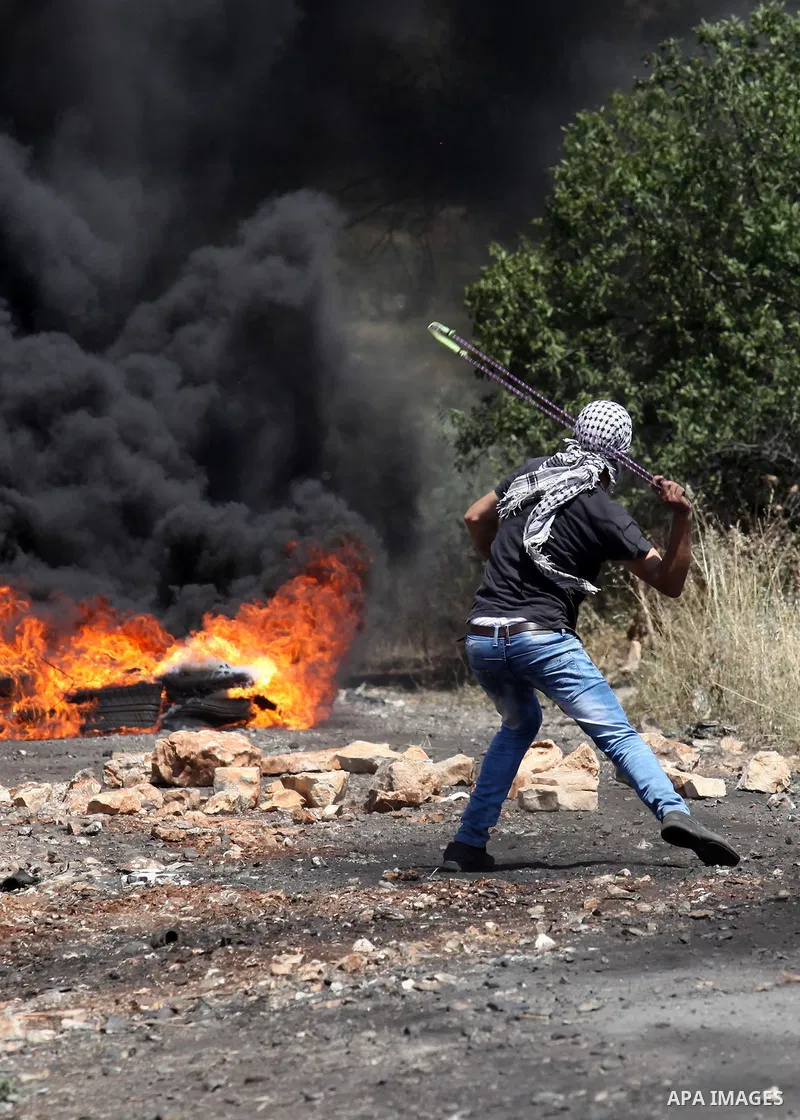A Palestinian protester hurls stones towards a digger operated by Israeli security forces during clashes following a demonstration against the expropriation of Palestinian land by Israel on April 29, 2016 in the village...