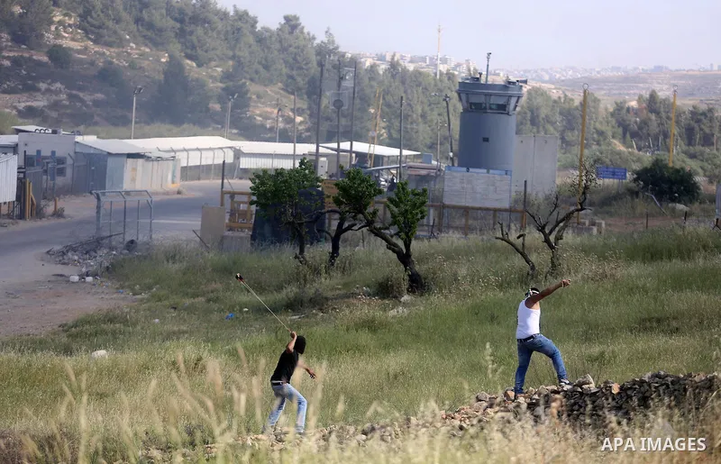 Palestinian protesters use a slingshot to hurl stones towards Israeli security forces during clashes on April 29, 2016, following a demonstration in solidarity with Palestinian prisoners held in Israeli jails, outside th...