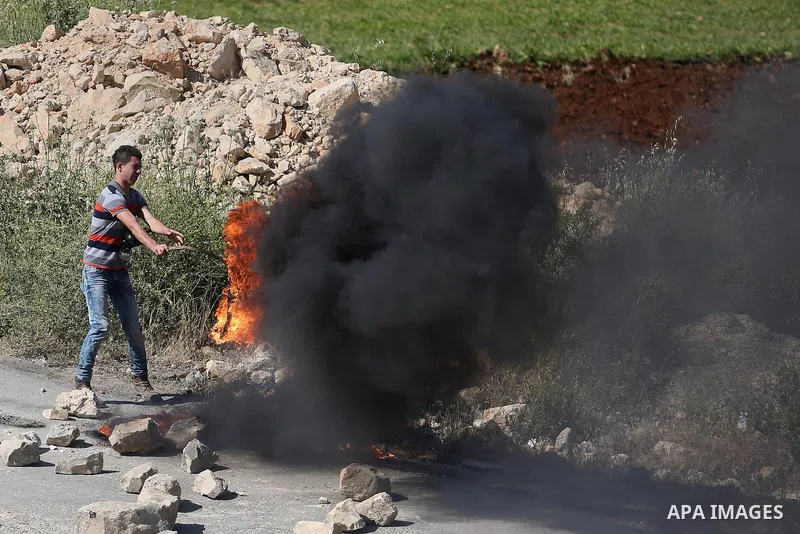 A Palestinian protester burns tires during clashes Israeli security forces on April 29, 2016, following a demonstration in solidarity with Palestinian prisoners held in Israeli jails, outside the compound of the Israeli-...