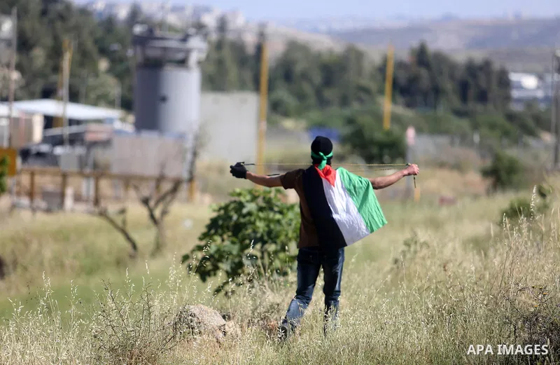A Palestinian protester uses a slingshot to hurl stones towards Israeli security forces during clashes on April 29, 2016, following a demonstration in solidarity with Palestinian prisoners held in Israeli jails, outside...