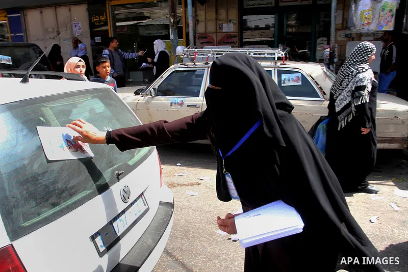 Palestinian women supporting Hamas movement distribute posters during awareness campaign against collaborate with Israel, in Rafah in southern Gaza strip, on April 30, 2016. Photo by Abed Rahim Khatib