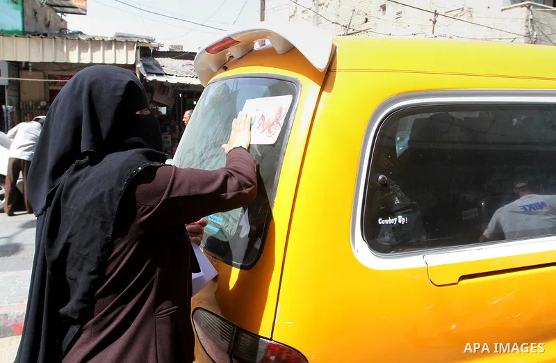 Palestinian women supporting Hamas movement distribute posters during awareness campaign against collaborate with Israel, in Rafah in southern Gaza strip, on April 30, 2016. Photo by Abed Rahim Khatib