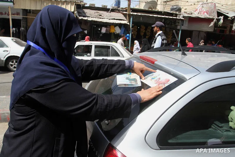 Palestinian women supporting Hamas movement distribute posters during awareness campaign against collaborate with Israel, in Rafah in southern Gaza strip, on April 30, 2016. Photo by Abed Rahim Khatib