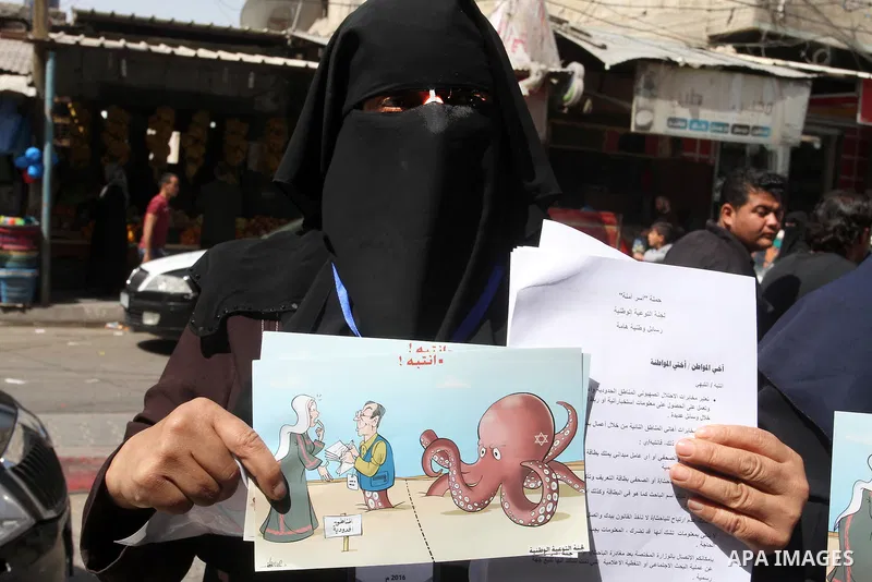 Palestinian women supporting Hamas movement distribute posters during awareness campaign against collaborate with Israel, in Rafah in southern Gaza strip, on April 30, 2016. Photo by Abed Rahim Khatib
