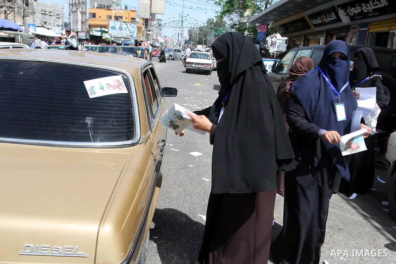 Palestinian women supporting Hamas movement distribute posters during awareness campaign against collaborate with Israel, in Rafah in southern Gaza strip, on April 30, 2016. Photo by Abed Rahim Khatib