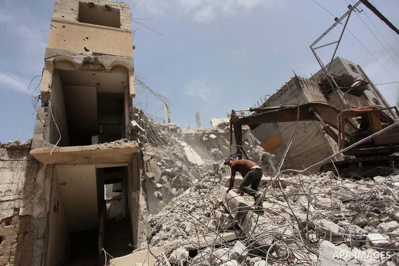 Palestinian men work on the remains of a building destroyed during the recent Israeli war 2014, in Shijaiyah neighborhood in the east of Gaza city, on April 30, 2016. Israel’s punitive ban on cement imports into the Gaza...